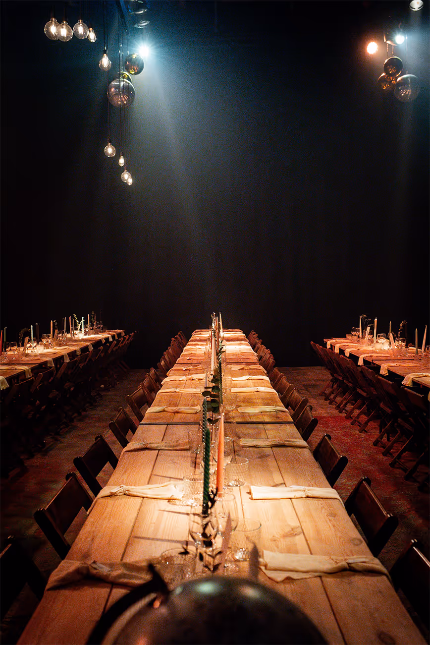 Feestelijk gedekte tafels met kaarsen en servetten.