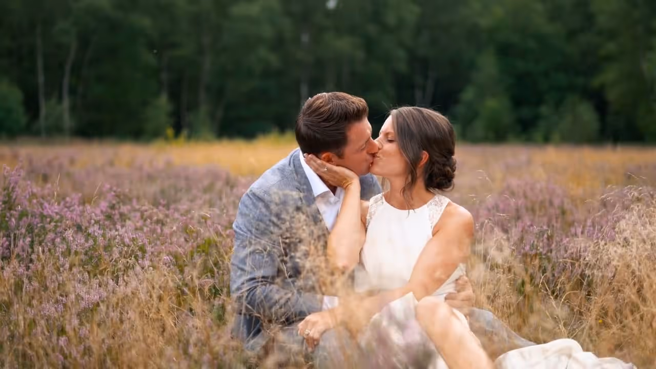 Trouw fotografie van een kussende bruid en bruidegom in een bloemenveld.